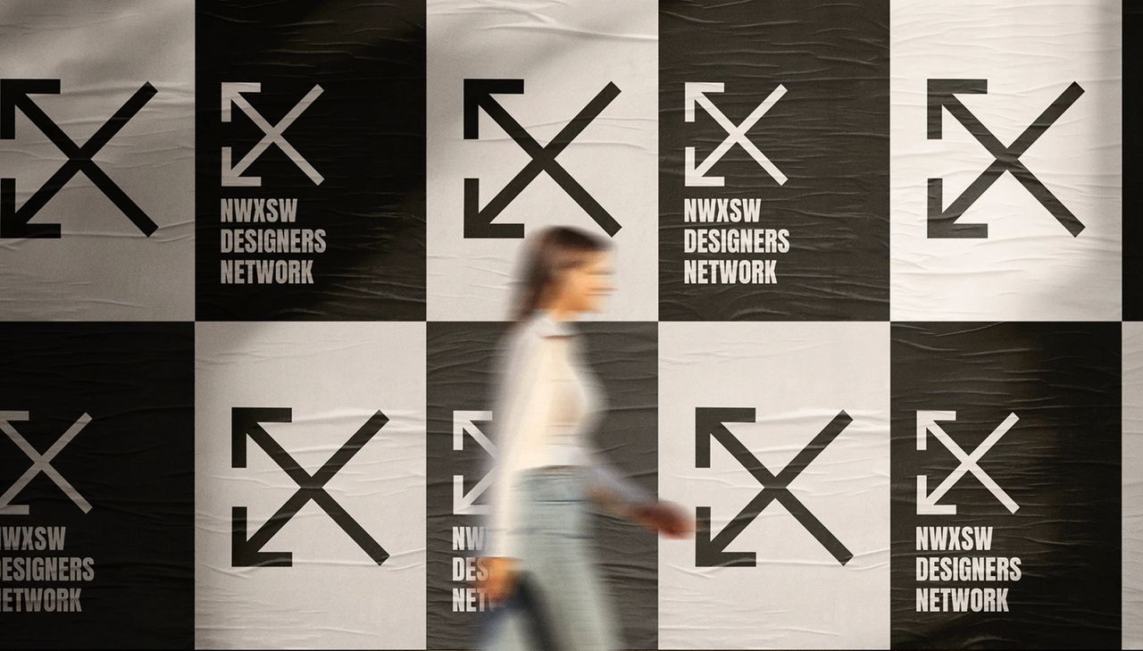 A woman walking past a wall of black and white NWXSW Designers Network posters